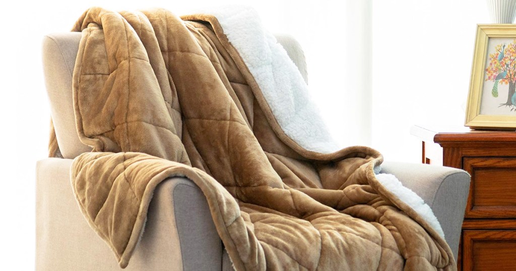 tan sherpa fleece weight blanket on a cream colored accent chair