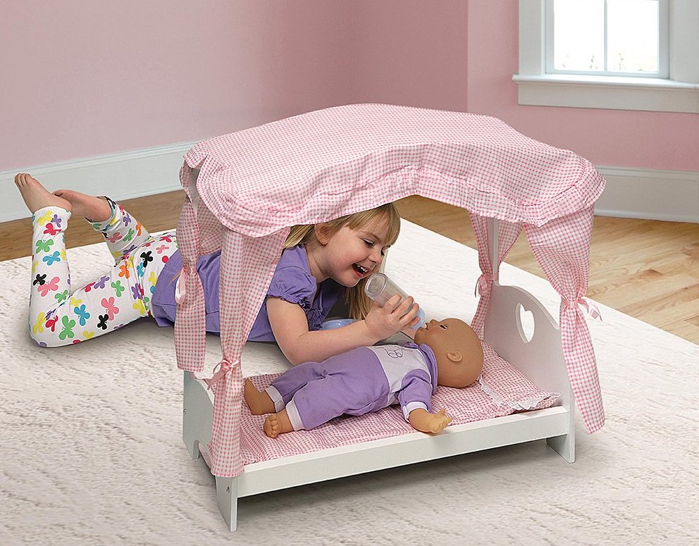 girl playing with doll laying in Badger Basket Canopy Bed