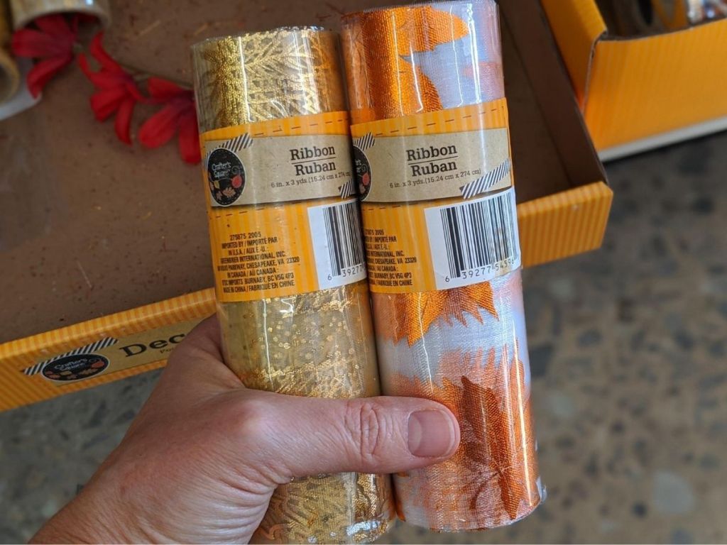 man's hand holding two rolls of ribbon