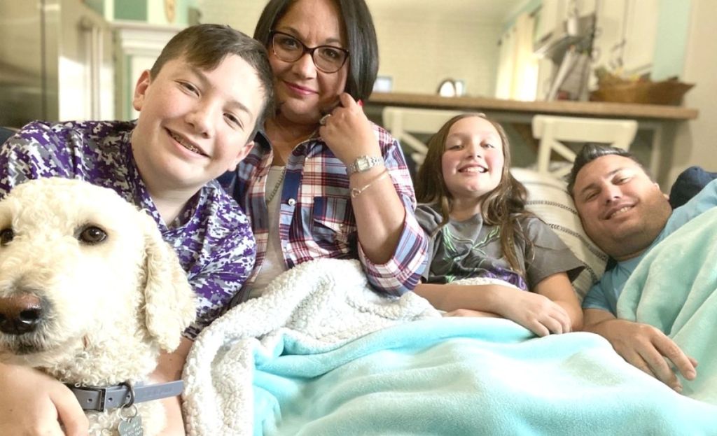 A family sitting on a couch together under a blanket