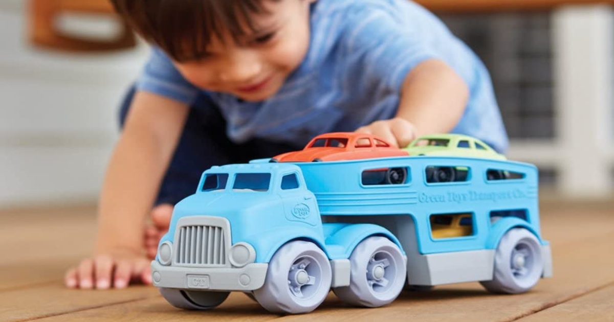 boy playing with truck car carrier on a wooden floor