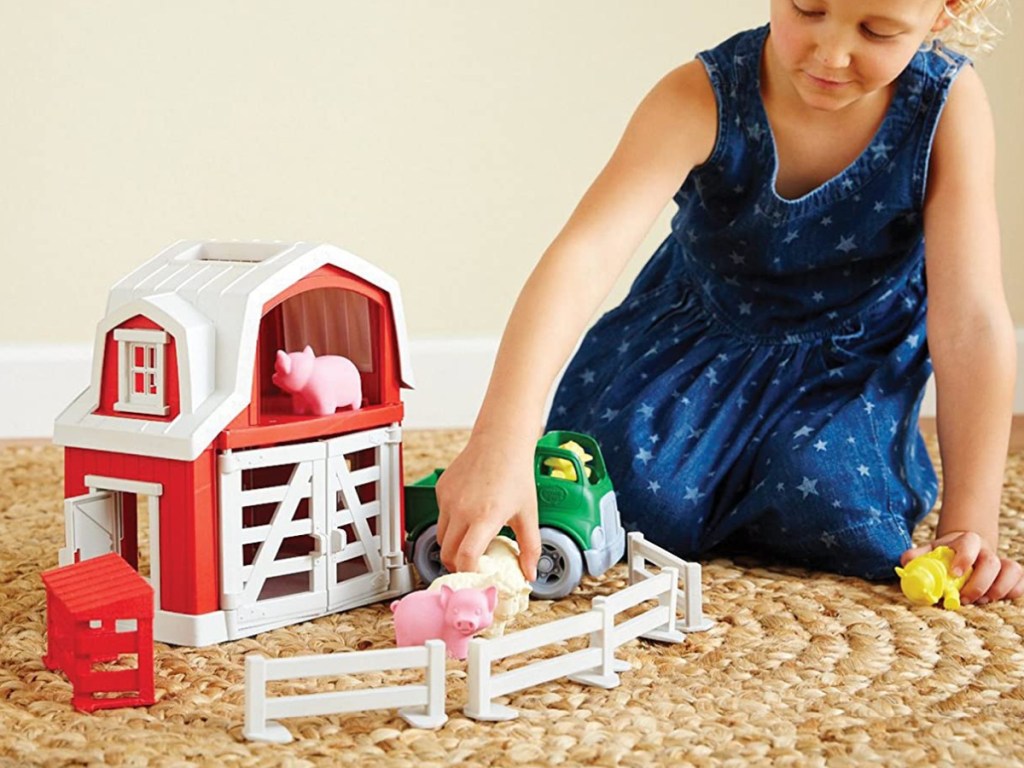 girl playing with toy farm set on carpet