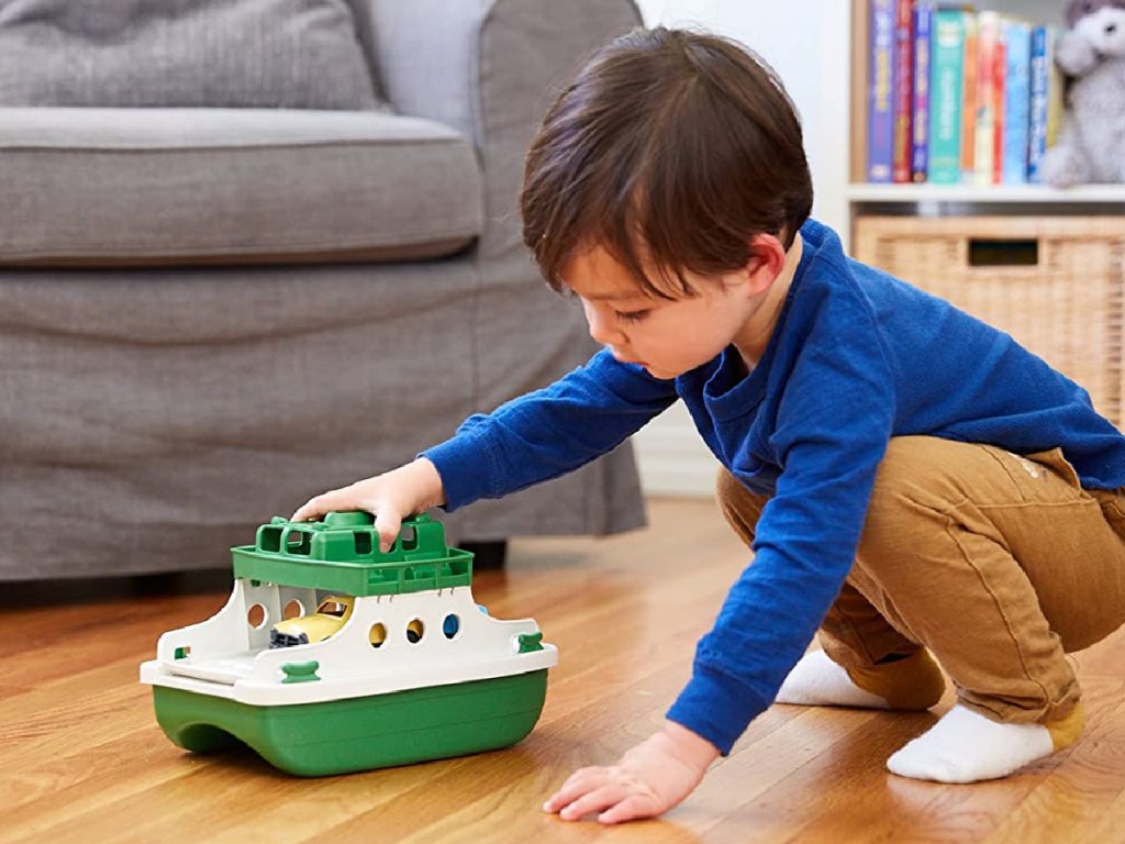 boy playing with toy ferry boat on hardwood floor