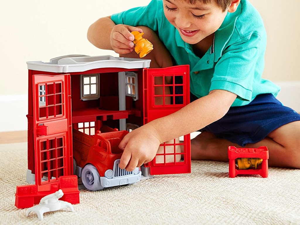 boy playing with fire station toy set on floor