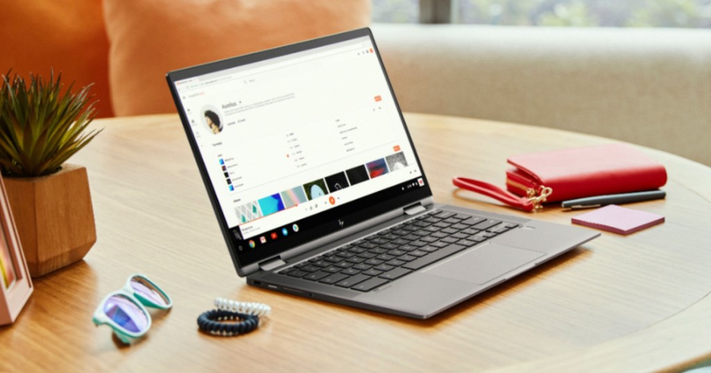 grey HP Chromebook on wood table with glasses, hair ties, and wallet near it