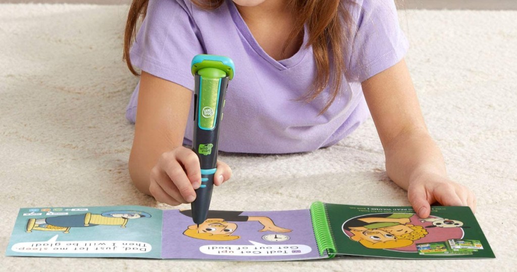 girl using LeapFrog LeapStart Go System with book on the floor