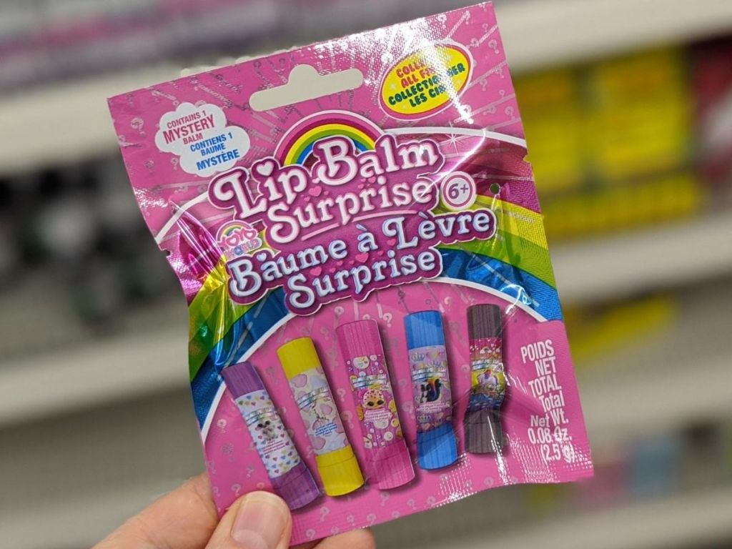 person's hand holding plastic package of mini lip balms