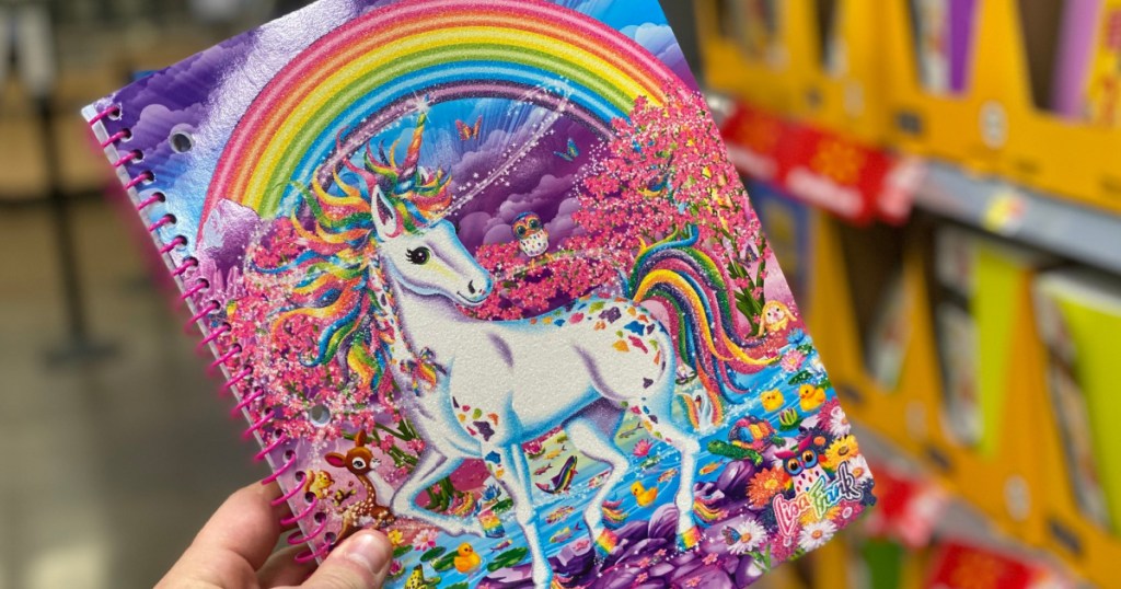 hand holding Lisa Frank Unicorn and rainbow notebook