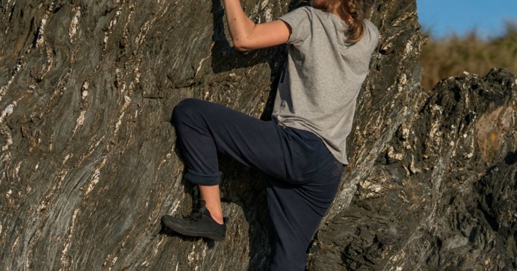 woman climbing rock face wearing hiking shoes