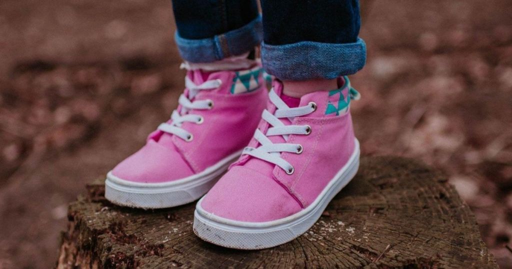 girl wearing high top sneakers on tree stump