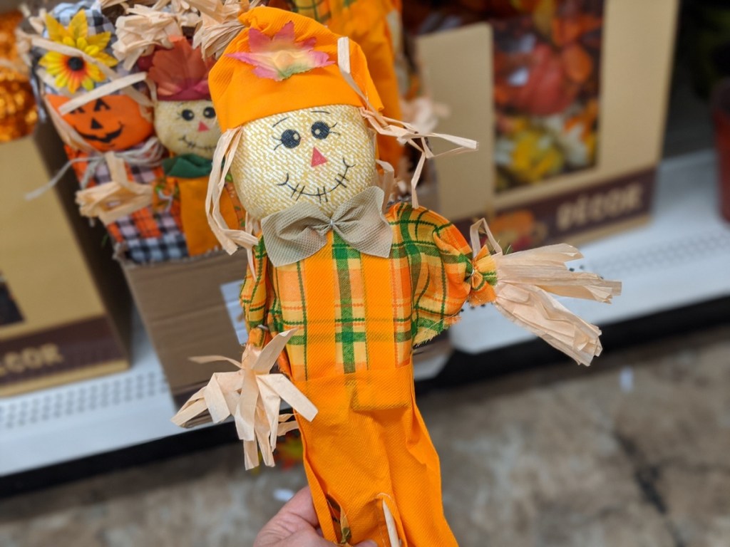 hand holding orange colored standing scarecrow at dollar tree