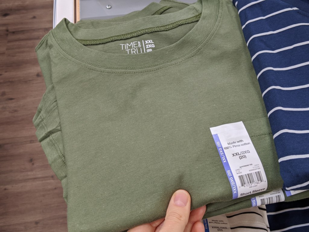 hand holding onto a green folding shirt in store