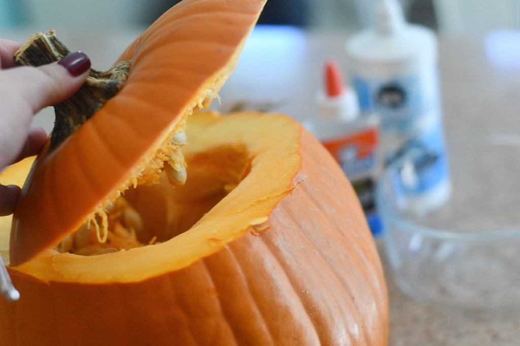 lifting top of cut pumpkin