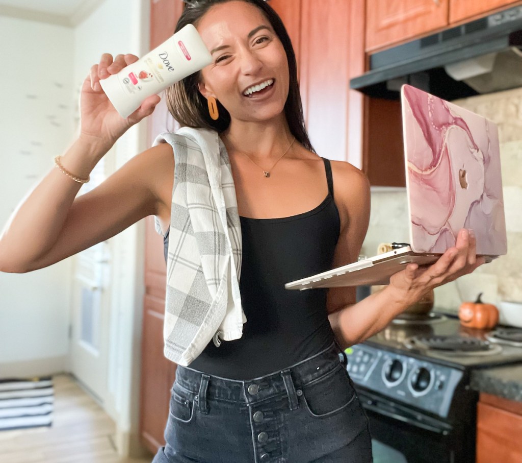 woman holding up dove deodorant and laptop standing in kitchen how to keep armpits from smelling without deodorant