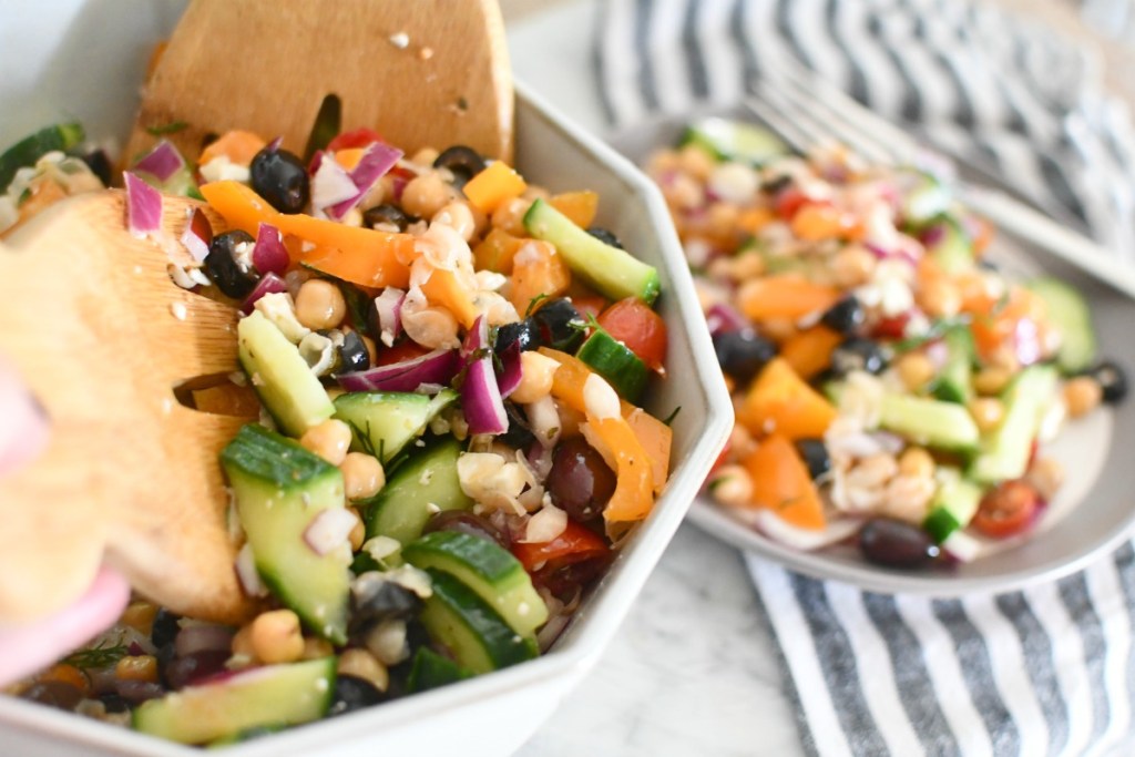 dishing up greek chickpea salad onto a plate