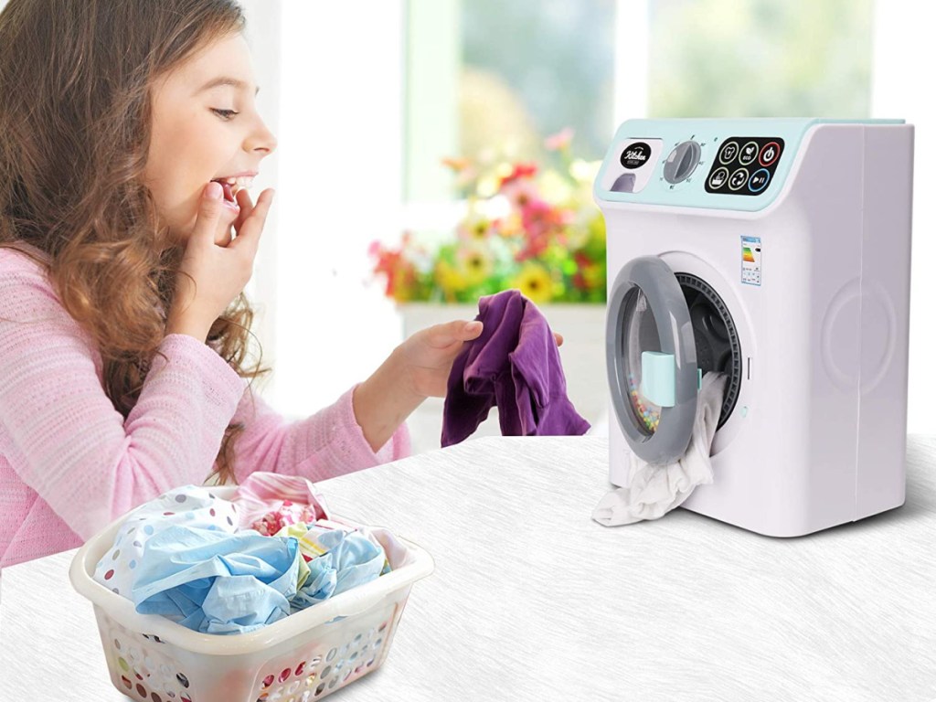 girl playing with toy washing machine and small basket of laundry