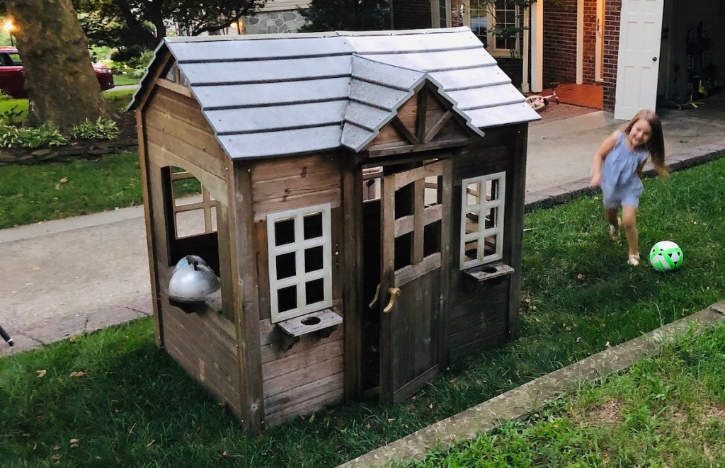 dirty kids playhouse sitting in yard on grass