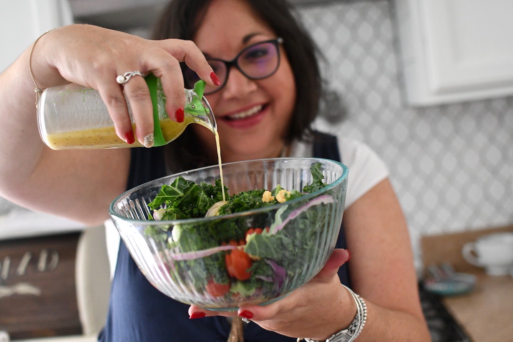 Lina pouring dressing into salad 