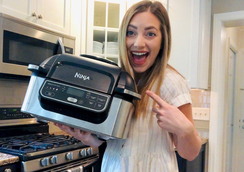 woman holding ninja foodi grill in kitchen