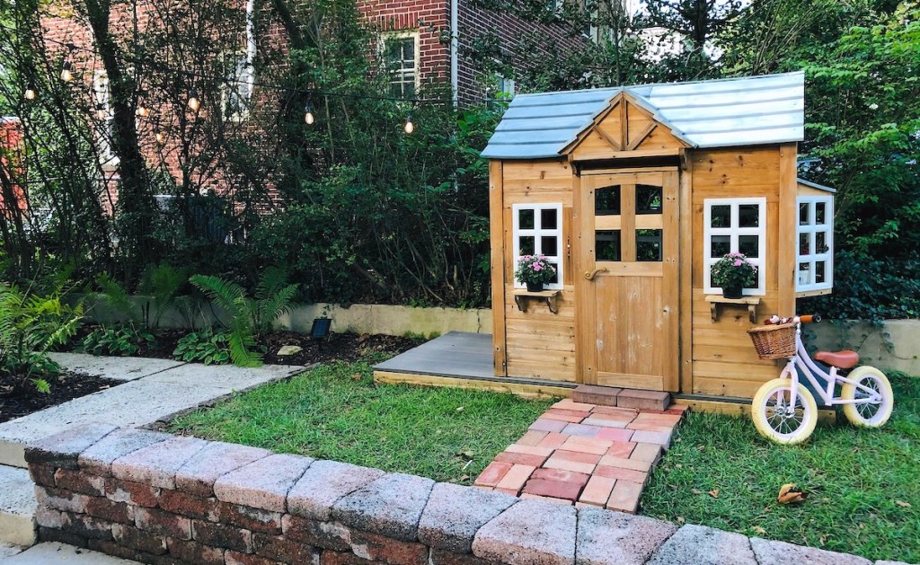 kids playhouse outside in grass with bike