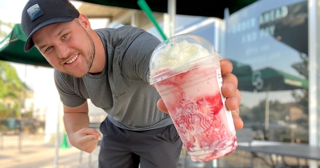 man holding a starbucks skittles frappuccino