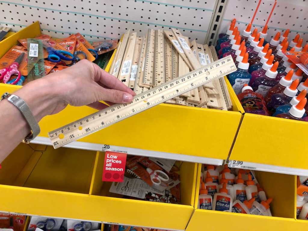 woman's hand holding up and up wood ruler