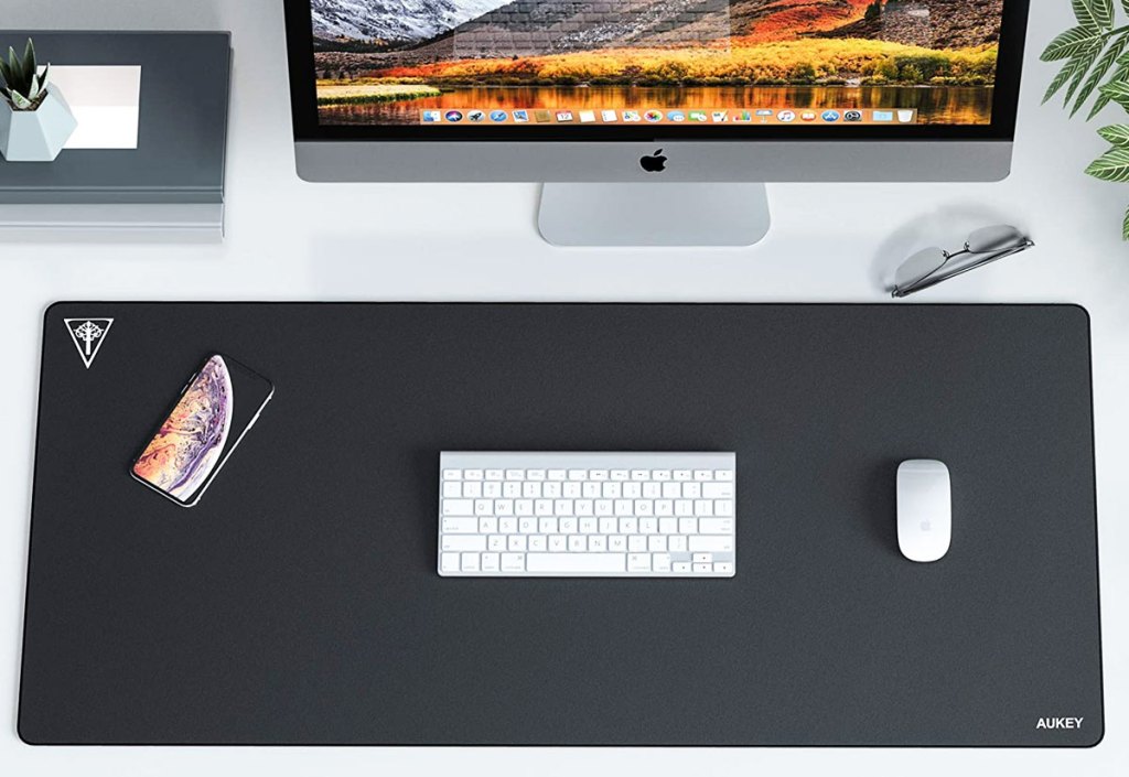 large black gaming keyboard under white keyboard and mouse in front of imac