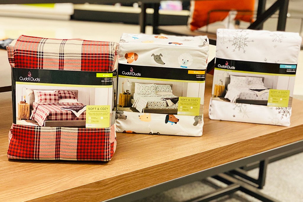 three sets of printed flannel sheet sets on a Kohl's display table