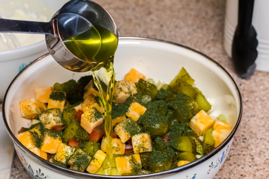 adding oil and dill to pasta salad