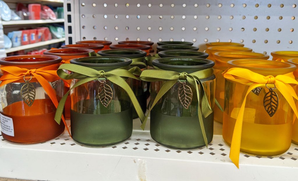 orange, green, and yellow glass candle holders with ribbon and gold metallic leaf on each one