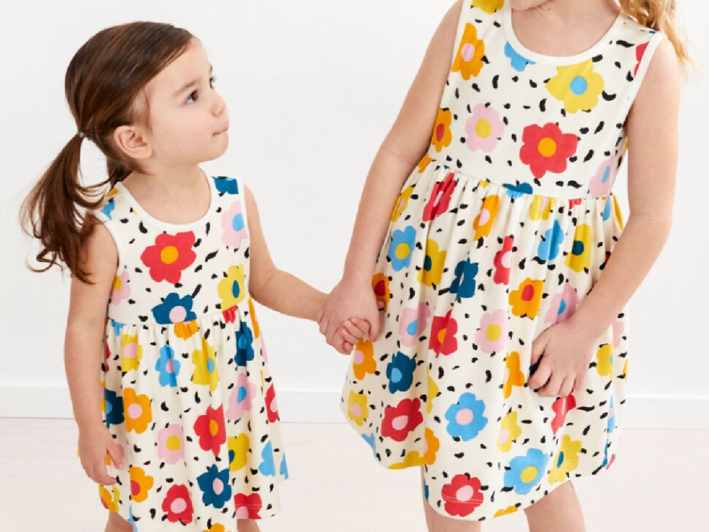 2 little girls wearing bright floral sleeveless dresses