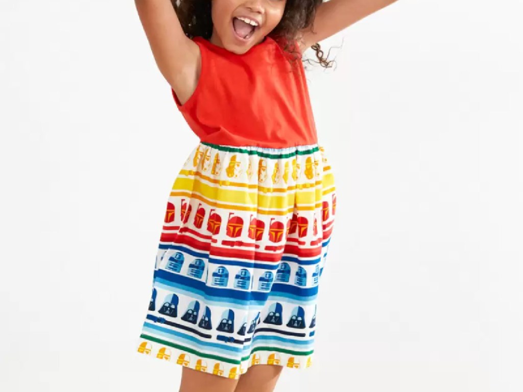 little girl jumping in the air wearing a bright rainbow colored sleeveless star wars dress