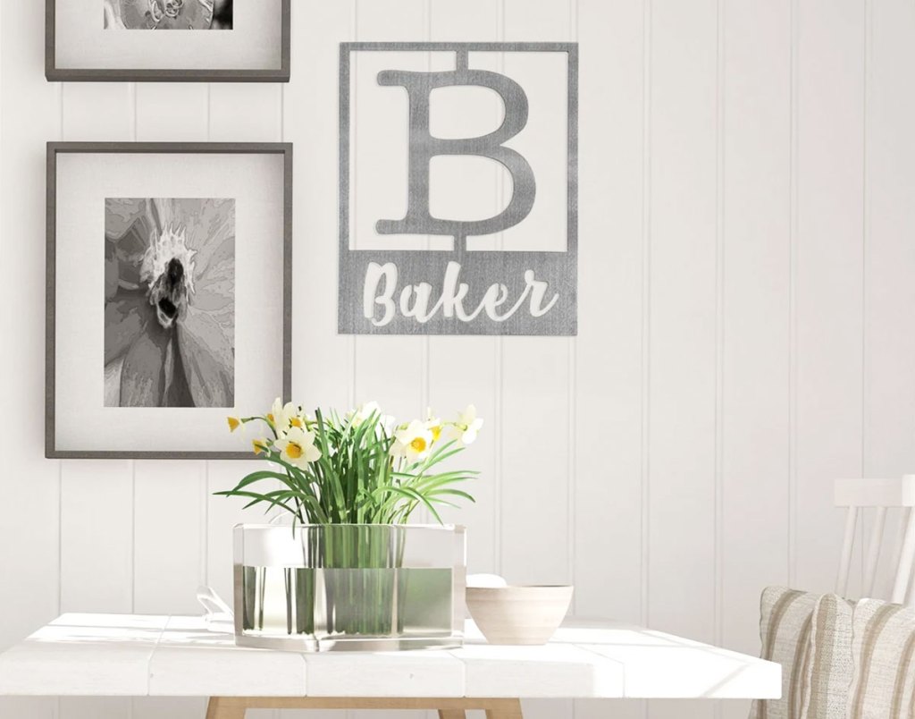 steel monogrammed plaque on wall with large B that says Baker next to other framed photos