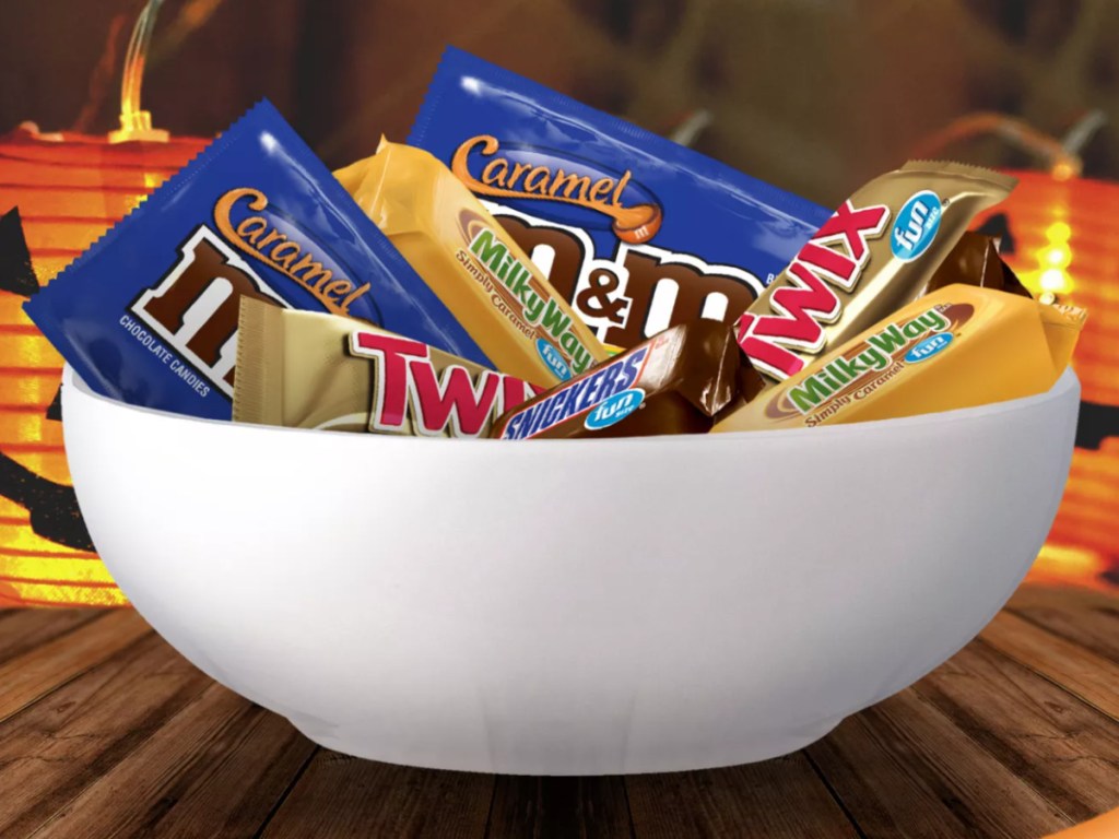 Large bowl of Halloween Candy in front of several lighted jack-o-lanterns