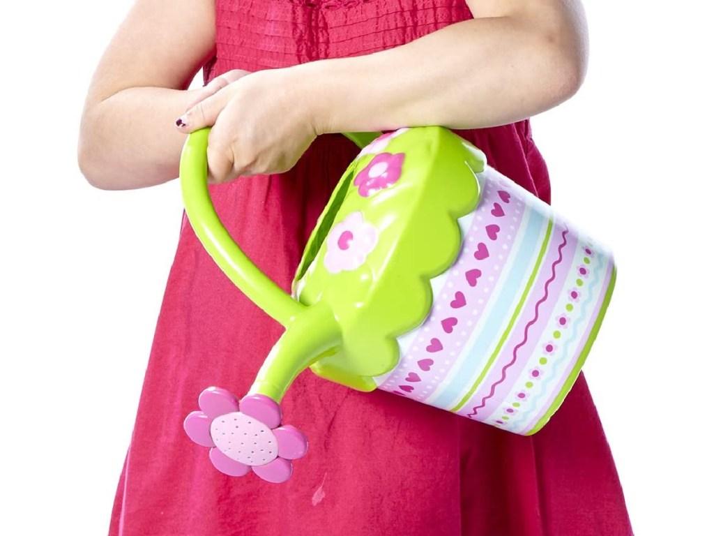 little girls wearing a bright pink dress holding a pink and green plastic watering can