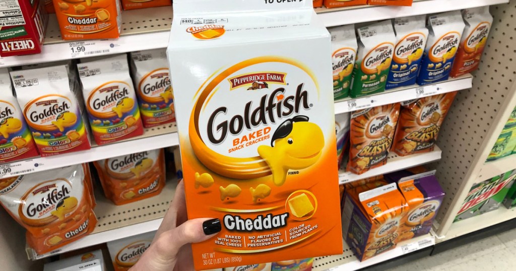 woman's hand holding large carton of cheddar goldfish crackers in store