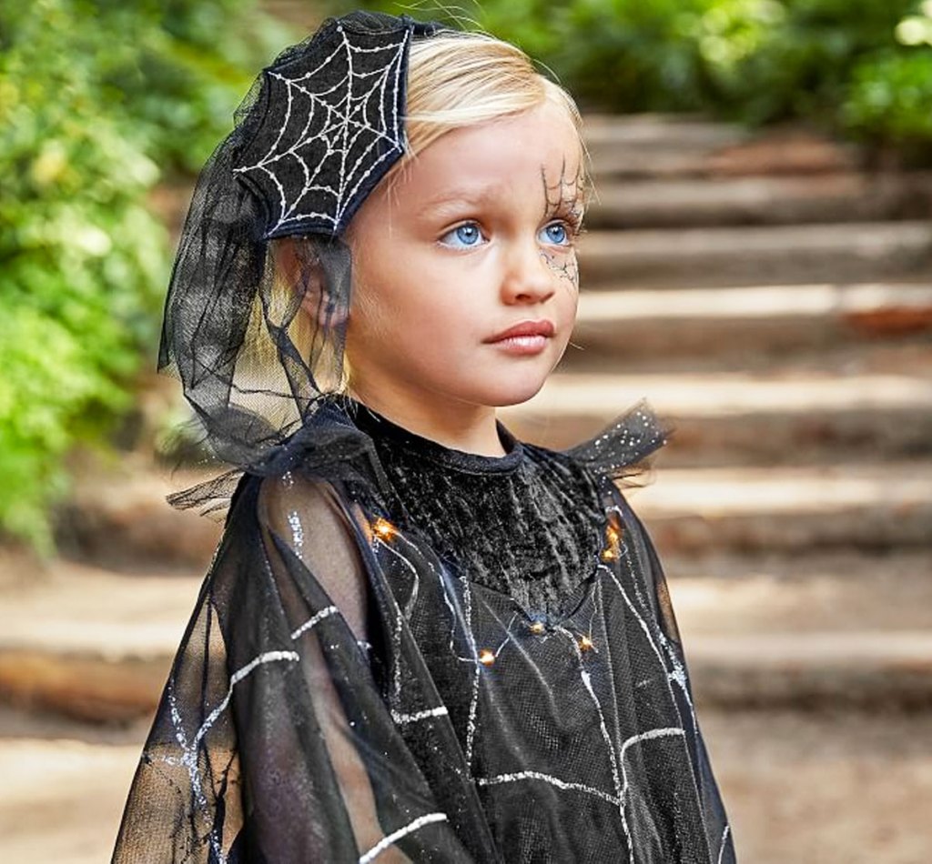 girl with blonde hair dressed in black dress with silver spider web details and spider web accessory in her hair