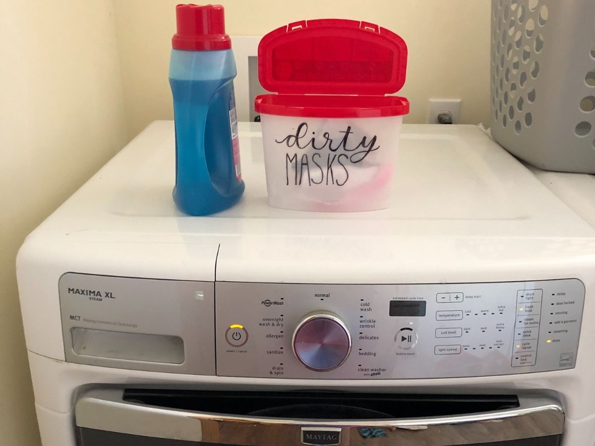 Persil liquid laundry detergent and container with "dirty masks" lettering sitting on washer