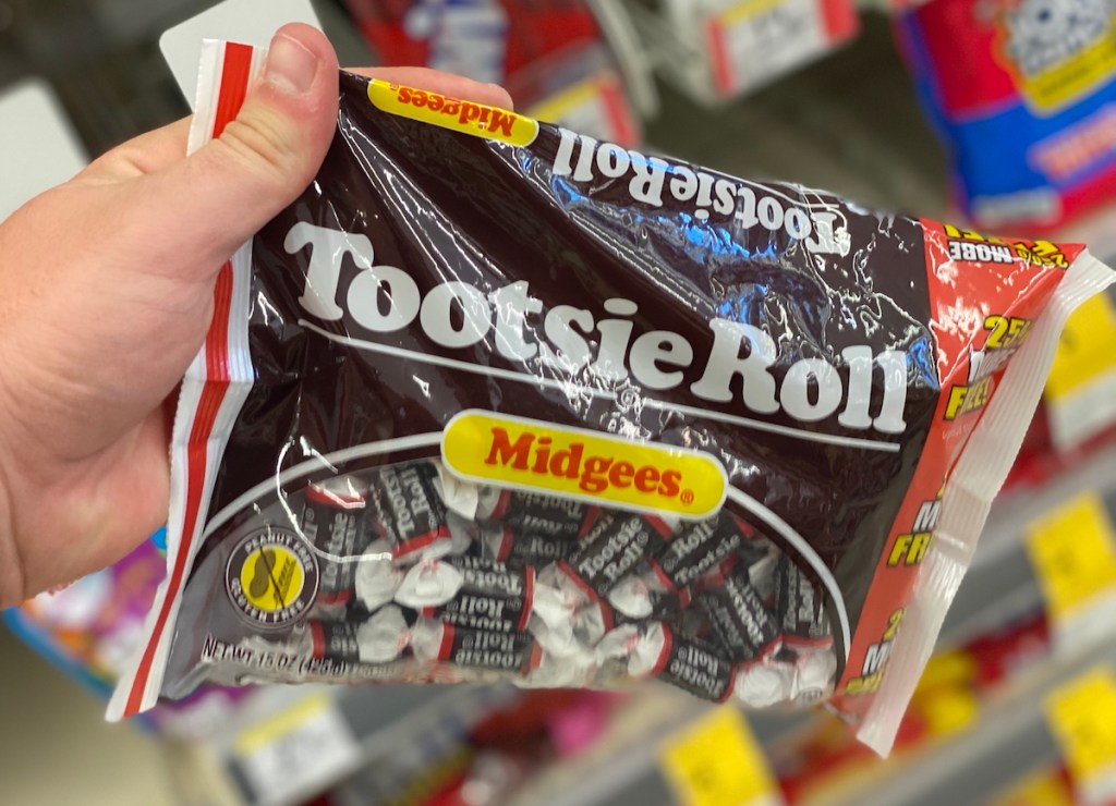 hand holding a bag of Tootsie Rolls