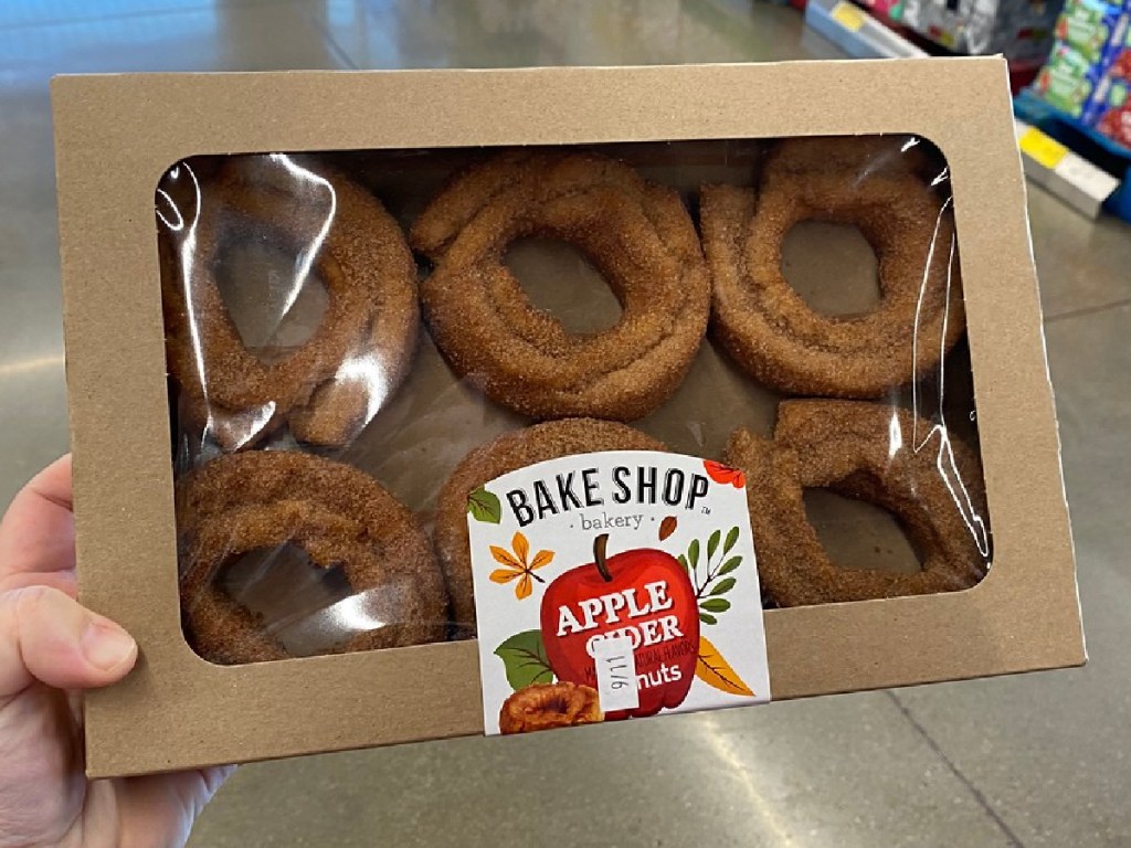 hand holding box of donuts that say "apple cider" on them