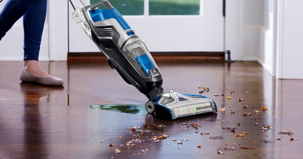 person pushing vacuum cleaner over wood floor mess