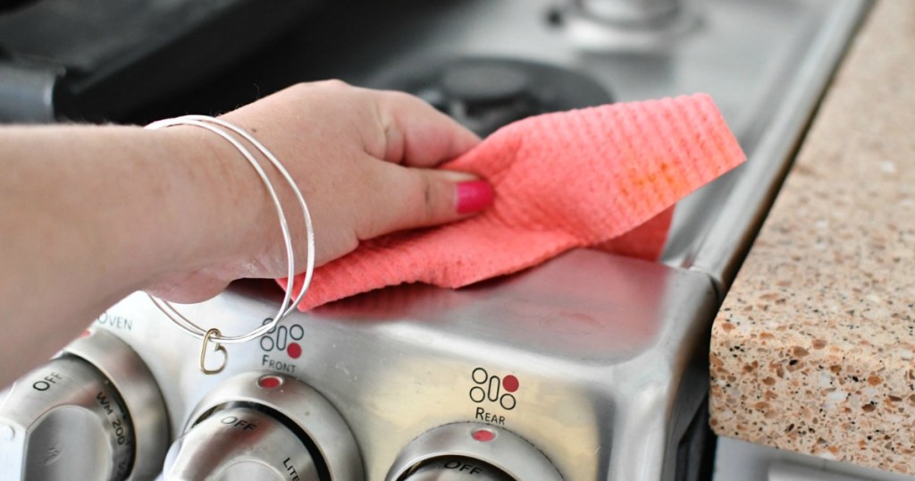 hand holding pink swedish dishcloth wiping stove top