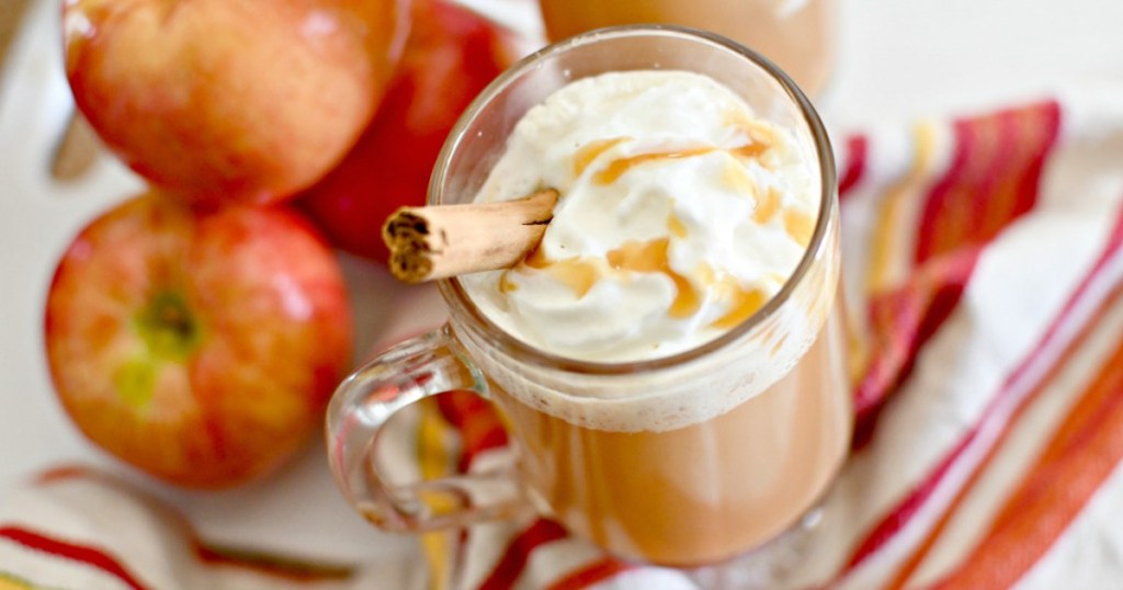 hot apple cider in glass cup with whipped cream and caramel sauce