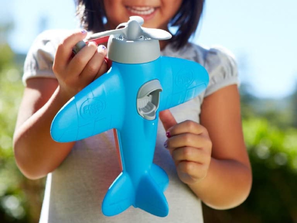 little girl holding blue airplane