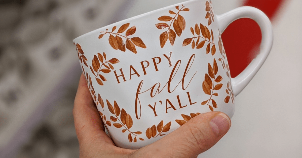 hand holding mug with fall leaves and words on it