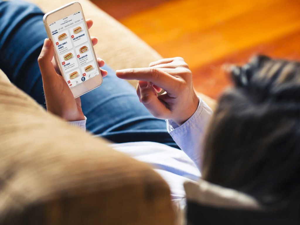 person laying on couch using cell phone app