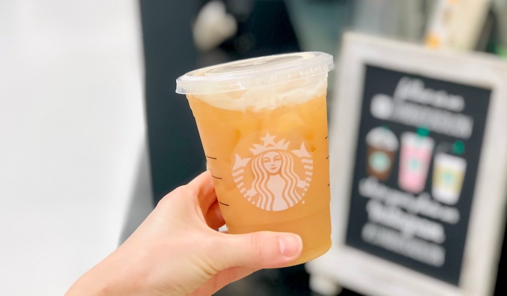 hand holding starbucks peach ring drink 