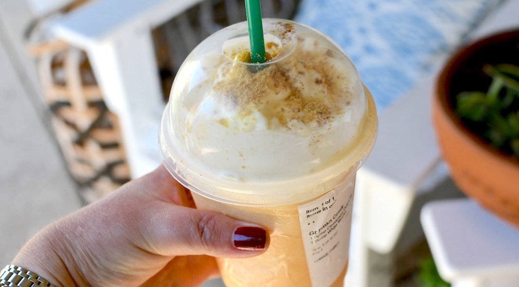 hand holding starbucks pumpkin frappuccino in hand