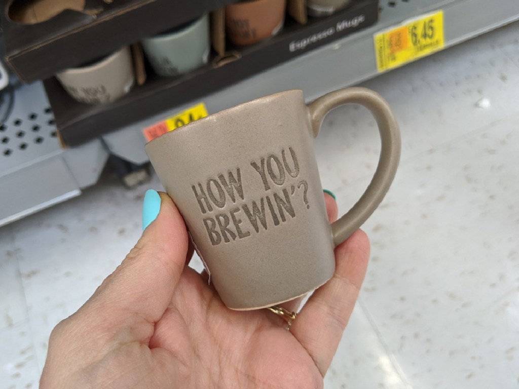 hand holding small mug that is used for expresso by store display