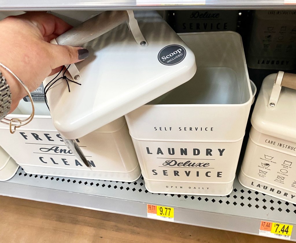 woman removing the lid off a large metal laundry container on walmart shelf